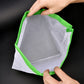 Green-trim reusable mesh food pouch with drawstring closure, held open by hands
