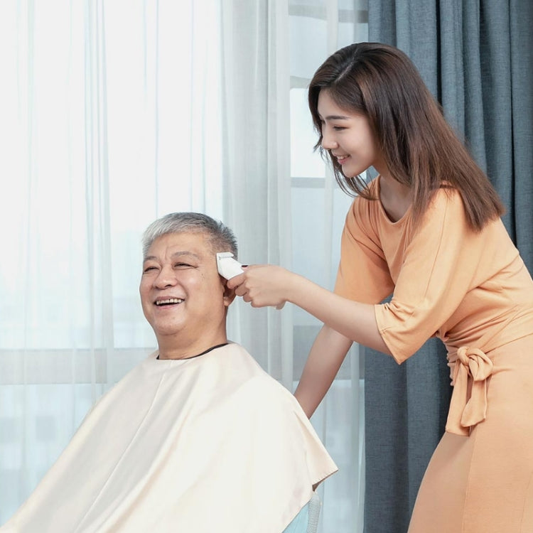 White handheld electric hair trimmer being used for haircut trimming