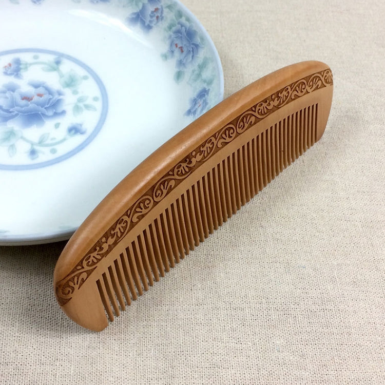 Brown wooden massage comb, curved handle with engraved floral trim and fine teeth