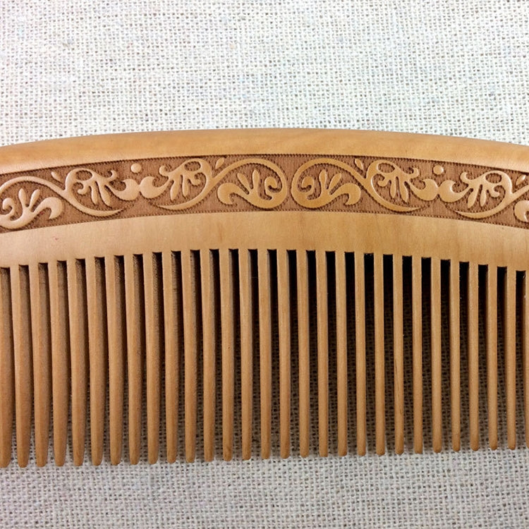 Close-up of brown comb teeth with engraved decorative border along top edge
