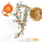 Artificial flower vine with orange daisy blossoms and green leafy sprigs, decorative length