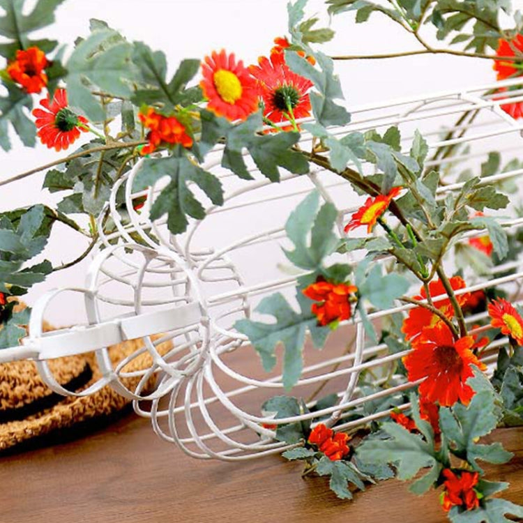 Close-up artificial flower vine with red-orange daisy blossoms and green leaves