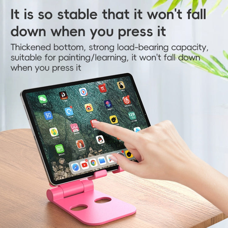 Foldable phone stand, pink, holding a tablet on a tabletop