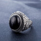 Men’s titanium steel ring with dark oval gemstone and patterned bezel, angled view