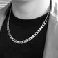Silver chain necklace worn on a crew-neck top, thick curb-link design