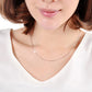 Thin silver snake-bone chain necklace worn at the neckline