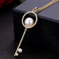 Gold key pendant necklace with round pearl center, rhinestone halo, and long key dangle