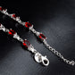 Silver bracelet close-up with red oval stones and lobster clasp end links.