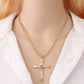 Gold rhinestone cross pendant necklace on a model wearing a white top