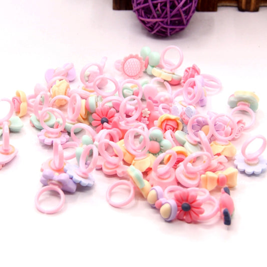 Bulk pile of pastel frosted resin kids rings with cartoon flower and animal designs