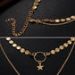 Gold layered chain necklace detail with star pendant, oval links, and ring clasp