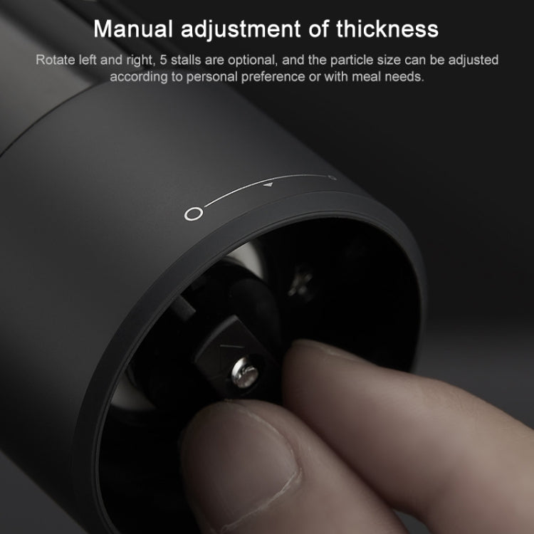 Black electric pepper grinder opening with adjustable dial, hand turning