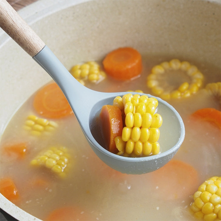 Gray silicone ladle with wood handle holding corn kernels in a cooking pot