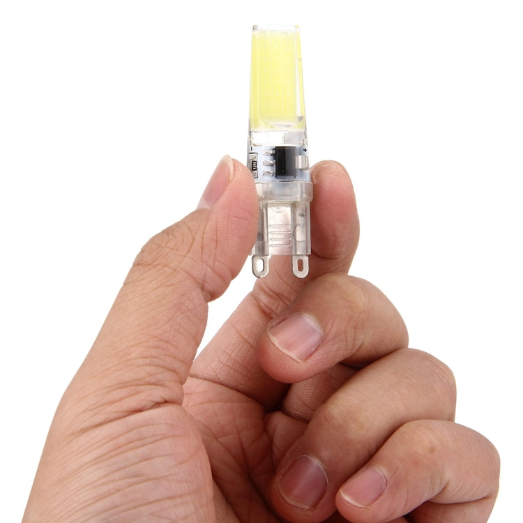 LED dimmable plug bulb held in hand, transparent body with yellow light strip
