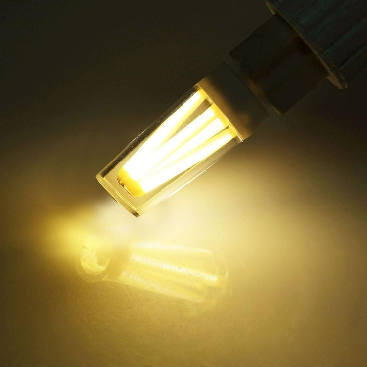 Lit E14 dimmable LED bulb with warm yellow glow, clear glass, silver screw base