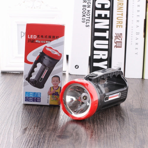 Black and red rechargeable LED flashlight on a wooden floor with retail box