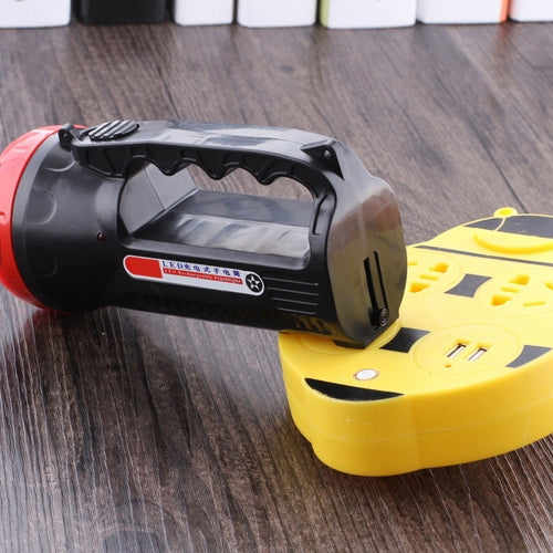 Black and red flashlight beside yellow charging base dock, rear view