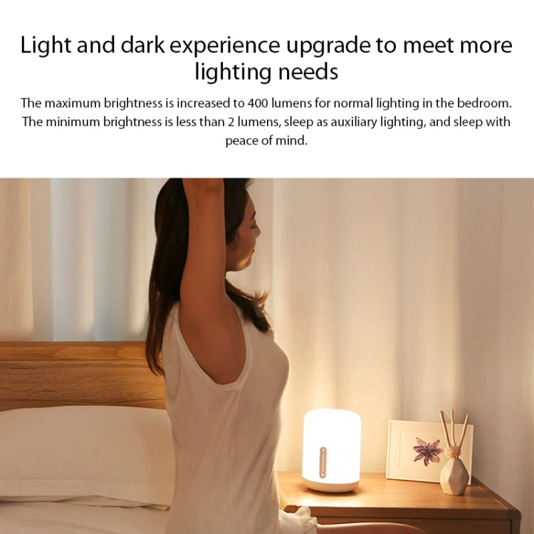 White bedside night light lamp glowing on a wooden nightstand
