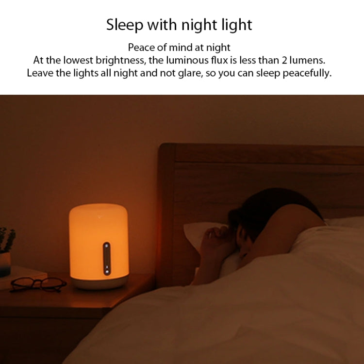White bedside night light lamp emitting dim warm light beside a bed
