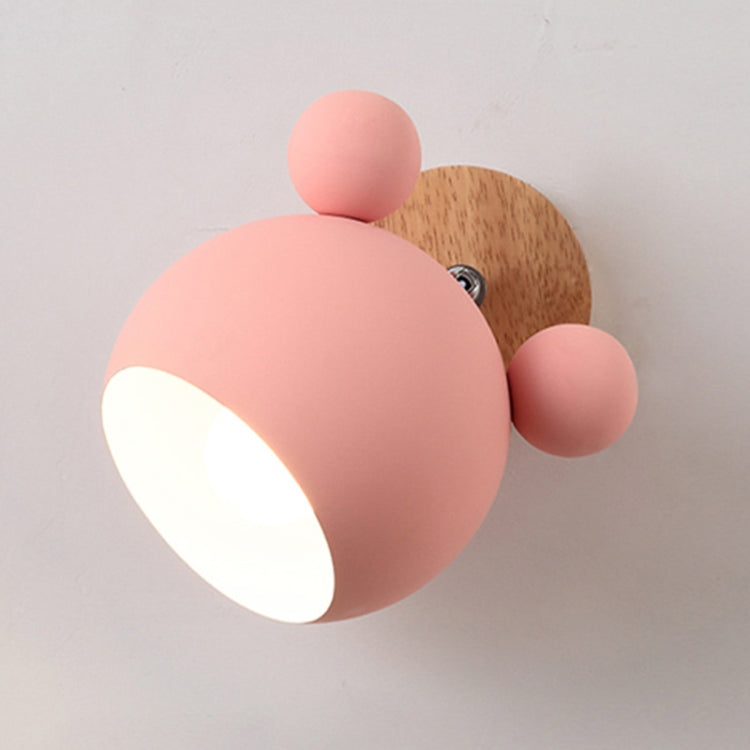 Pink round dome wall lamp with wooden backplate and two ball accents, lit spotlight.