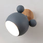 Dark gray round dome wall lamp with wooden backplate and three ball accents, glowing light.