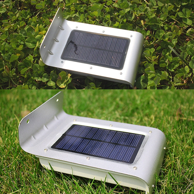 White solar wall light on grass with blue solar panel and base mounting