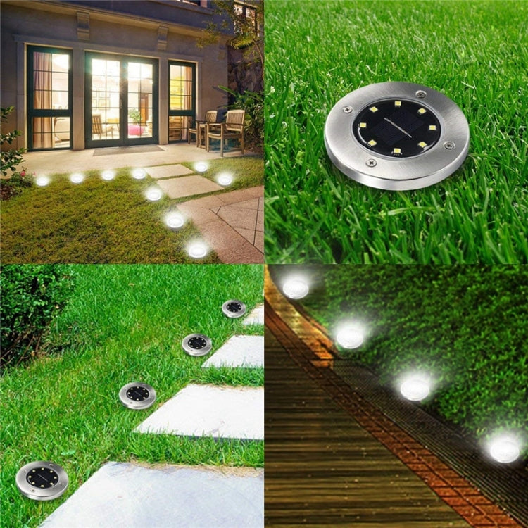 Solar LED buried ground lights in green grass, showing round silver tops and glow