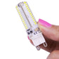 G9 LED light bulb held by hand, clear plastic housing and two-prong white base