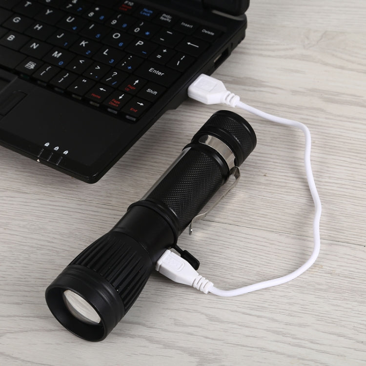Black USB charging LED torch flashlight connected to white cable near keyboard