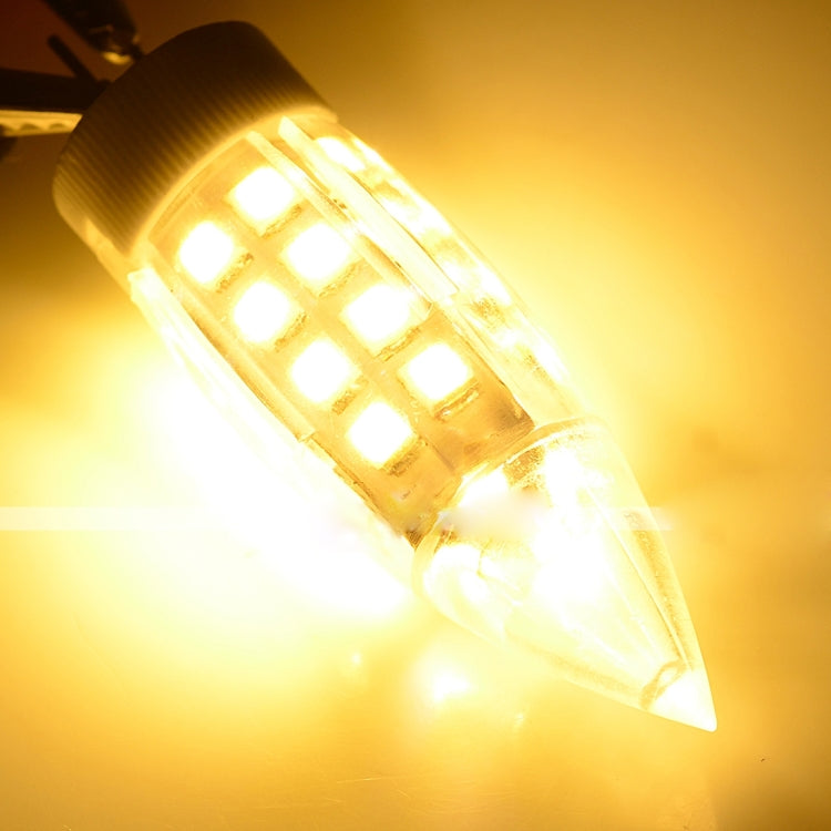 Lit LED bulb emitting warm yellow light from clear lens and SMD array