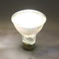 Lit MR16 LED spotlight in base, bright white light emitting through clear lens