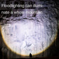 Flashlight beam illuminating a rocky wall and distant figure in the dark.