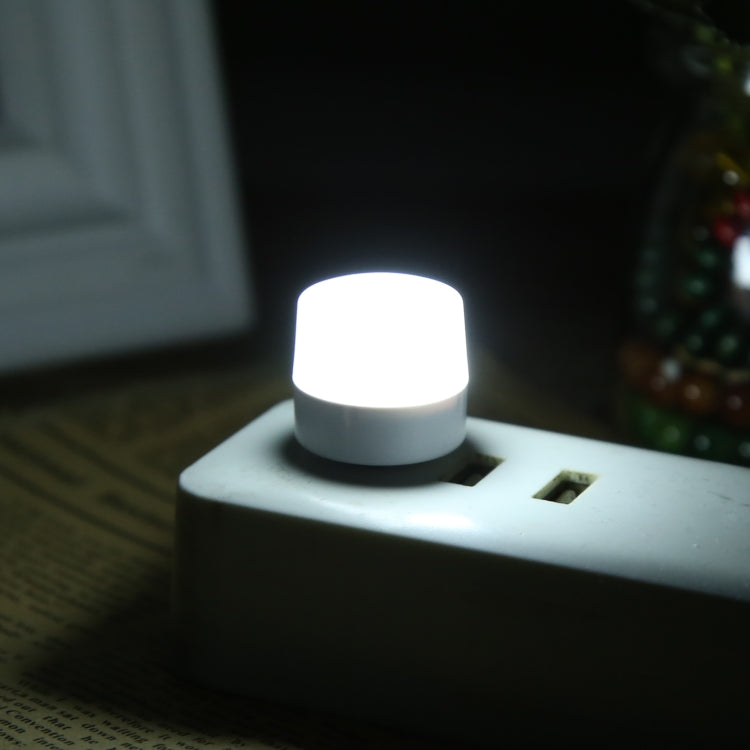 Round LED USB mini night light glowing from a USB port on a nightstand