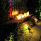 Outdoor solar spotlights casting warm light along pathway near garden