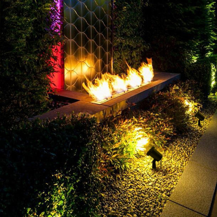 Outdoor solar spotlights casting warm light along pathway near garden