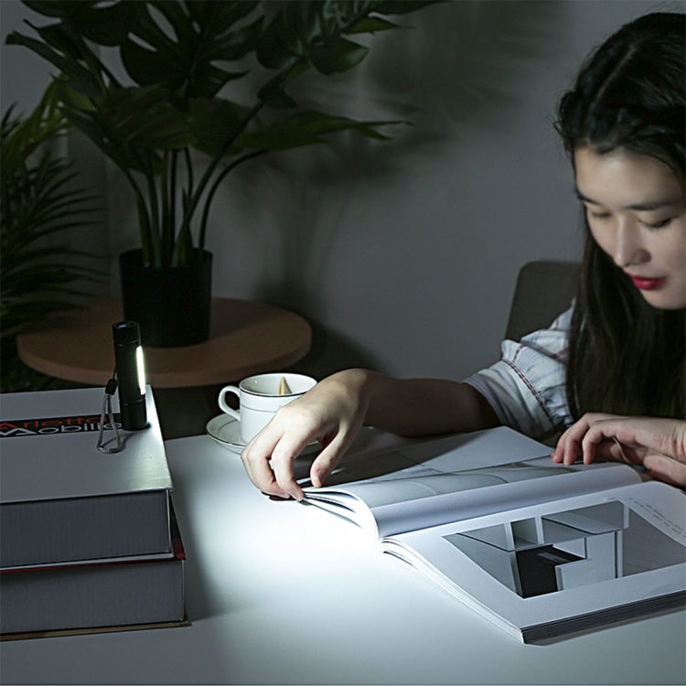 Handheld flashlight with bright beam illuminating paper on a desk