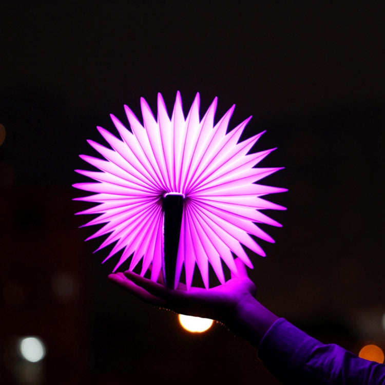 Purple-pink folding semicircle night light glowing, held by hand