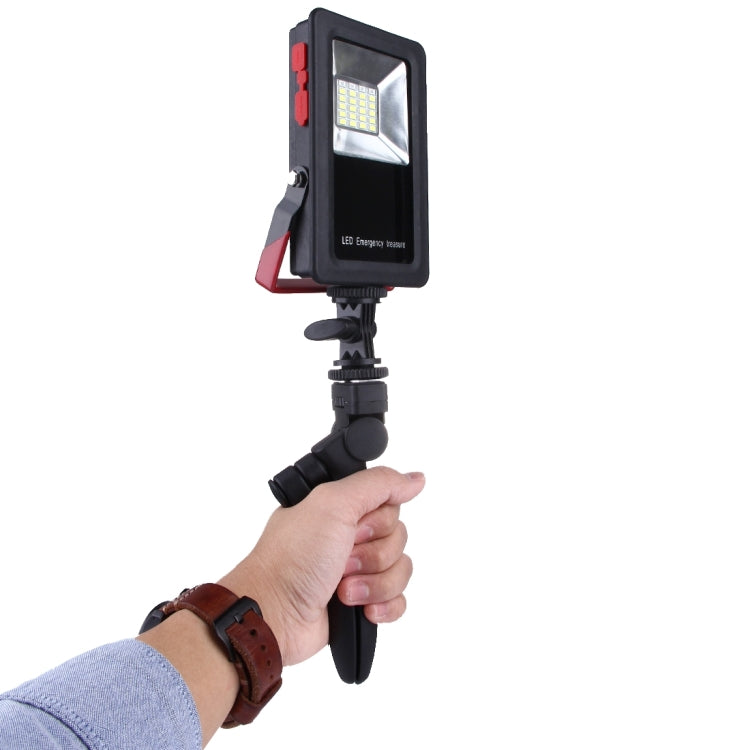 Black LED emergency light held in hand with front square LED panel