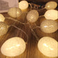 Close-up egg light string with warm white cotton-thread globe bulbs