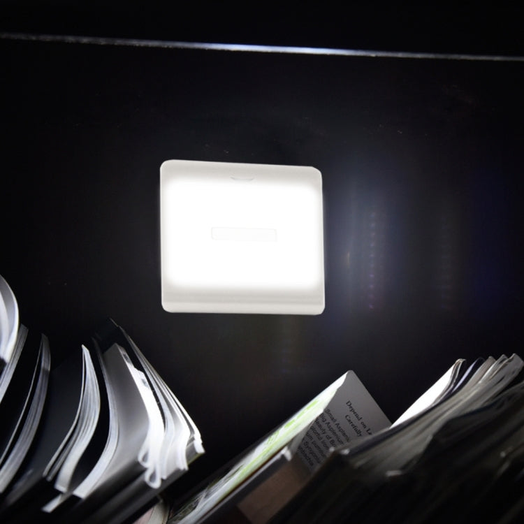 Square frosted LED night light glowing on dark wall