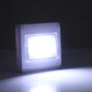 Square white night light lamp glowing brightly on a dark wall