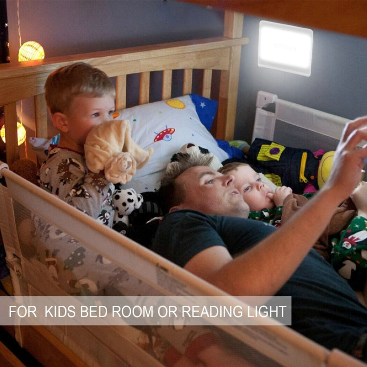 Square white bedside night light lamp switched on above a kids room bed