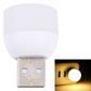 Mini USB night light glowing warm white, with silver USB plug visible behind.