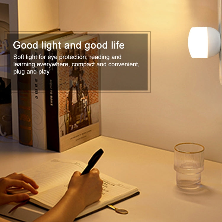 Mini USB night light on a desk, emitting a soft white glow near a book.