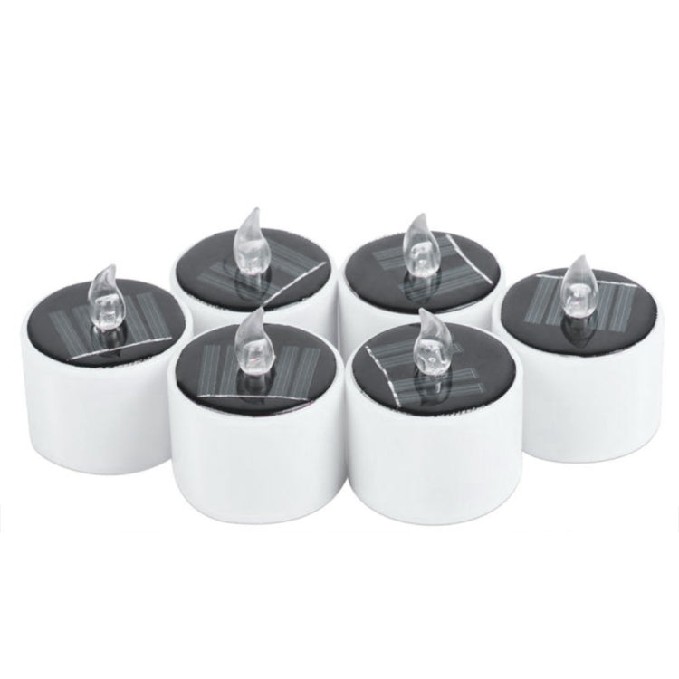 Group of white LED candle night lights with clear flame caps on dark round solar panels
