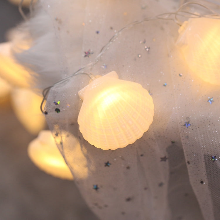 Warm shell LED fairy light bulb on clear wire with sheer fabric behind