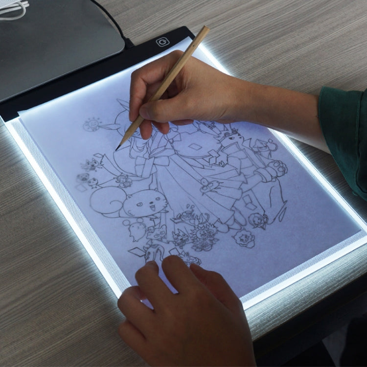 Portable A4 LED tracing light box, hands sketching on illuminated board