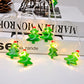 LED string lights with green tree ornaments wrapped around white cord