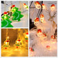 LED light string close-up of green tree and warm glowing snowman ornaments