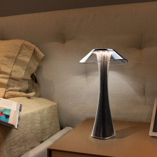 Dark ribbed LED table lamp with wide metallic shade, glowing light through the top.